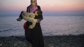 A Syrian migrant woman carries her child away upon their arrival by a dinghy at the southeastern Greek island of Kos, Greece, early Thursday, Aug. 20, 2015. Greece this year has been overwhelmed by record numbers of migrants arriving on its eastern Aegean islands, with more than 160,000 landing so far.  (AP Photo/Alexander Zemlianichenko)