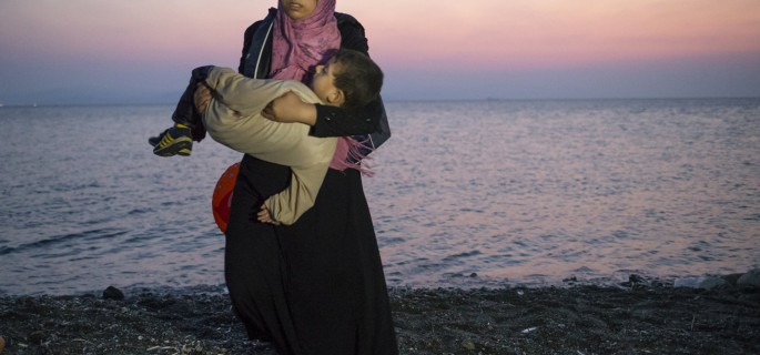 A Syrian migrant woman carries her child away upon their arrival by a dinghy at the southeastern Greek island of Kos, Greece, early Thursday, Aug. 20, 2015. Greece this year has been overwhelmed by record numbers of migrants arriving on its eastern Aegean islands, with more than 160,000 landing so far. (AP Photo/Alexander Zemlianichenko)